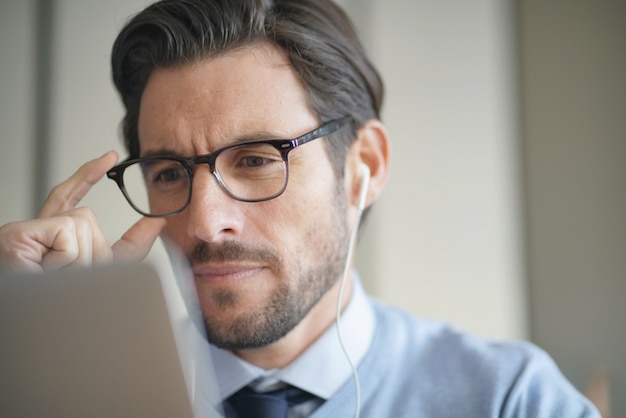 Portret van aantrekkelijke man aan het werk op laptop dragen van een bril