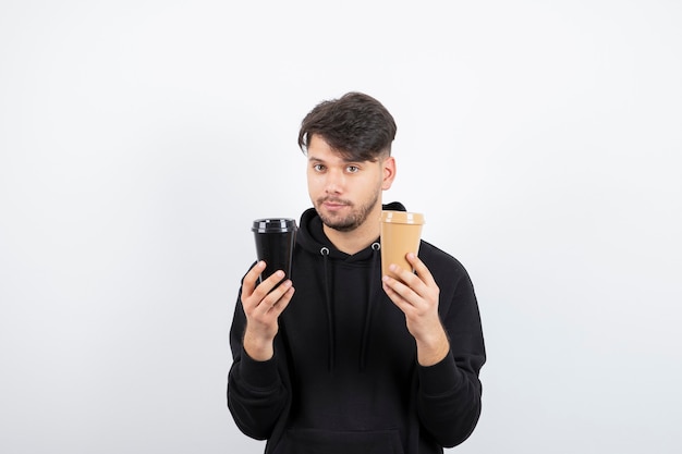 Portret van aantrekkelijke man met twee meeneembekers