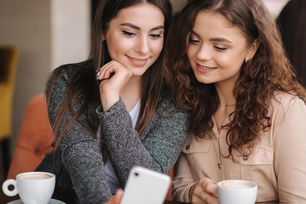 Portret van aantrekkelijke vrouwen kijken naar telefoon in café