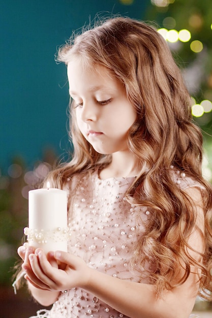 Portret van acute langharige meisje in jurk met lichten. Meisje bedrijf brandende kaars. Kerstmis, Nieuwjaar en verjaardagsviering concept. Kerstvakantie. Kopieer ruimte