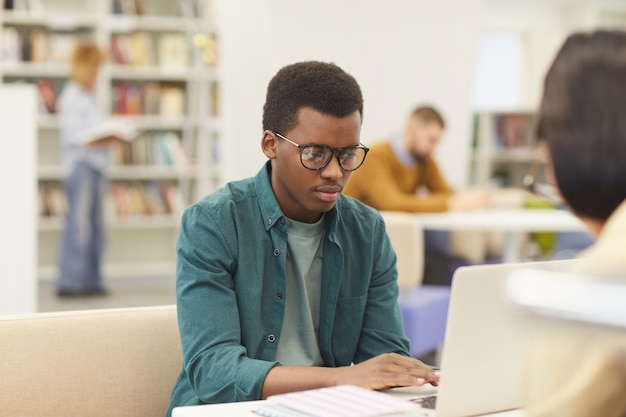 Portret van afrikaanse tiener die in universiteitsbibliotheek studeert