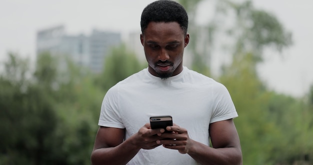 Portret van Afro-Amerikaanse man met pauze na fitnesstraining. Fitness man kijken naar smartphone fitness app na het hardlopen.