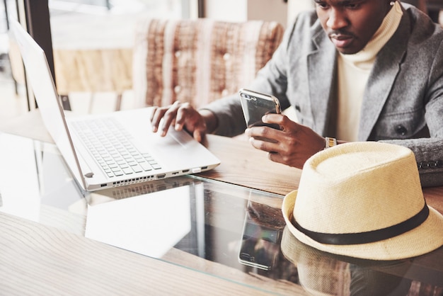 Portret van Afro-Amerikaanse man zit in een cafe en bezig met een laptop