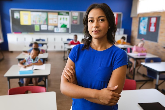 Portret van Afro-Amerikaanse vrouwelijke leraar met gekruiste armen in de klas op school