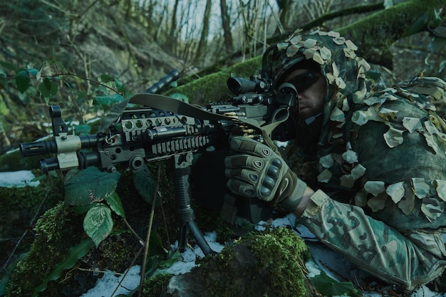 Portret van airsoft-speler in professionele uitrusting in helm gericht op slachtoffer met pistool in het bos. Soldaat met wapens in oorlog