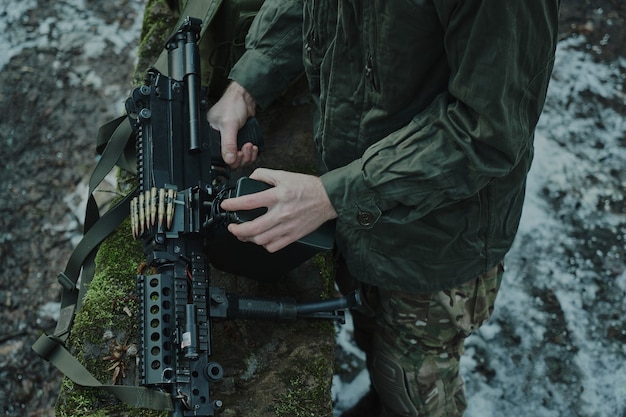 Portret van airsoft-speler in professionele uitrusting laadt een pistool met kogels in het bos. Soldaat met wapens in oorlog