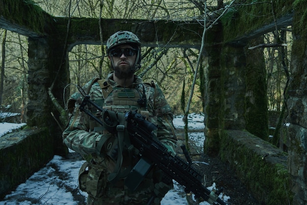 Portret van airsoft-speler in professionele uitrusting met machinegeweer in het bos. Soldaat met wapens in oorlog