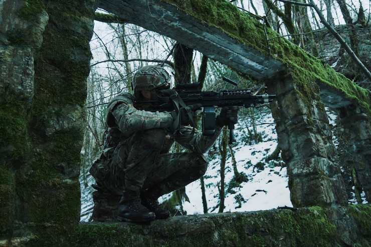Foto portret van airsoft-speler in professionele uitrusting met machinegeweer in het bos. soldaat met wapens in oorlog