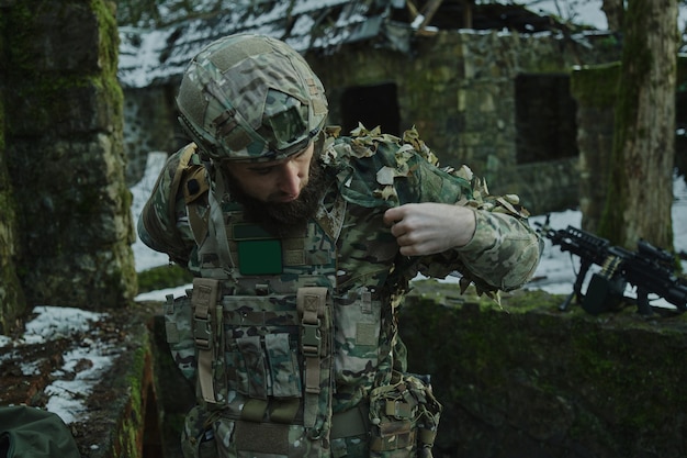 Portret van airsoft-speler in professionele uitrusting met machinegeweer in het bos. Soldaat met wapens in oorlog