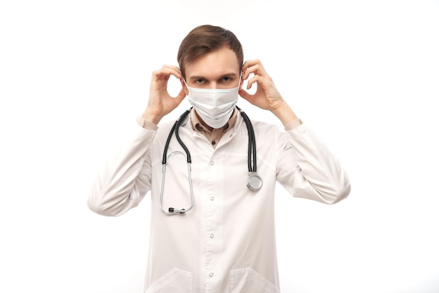 Portret van arts in witte medische jas en beschermend gezichtsmasker geïsoleerd op een witte achtergrond met kopie ruimte