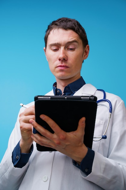 Portret van arts met stethoscoop en tabletcomputer in de hand op blauwe achtergrond