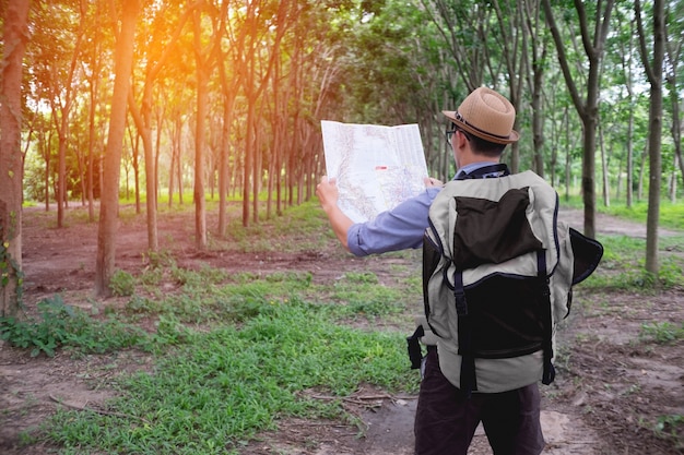 Portret van avontuurlijke man met kaart en extreme ontdekkingsuitrusting op bos met zonsopgang of zonsondergang