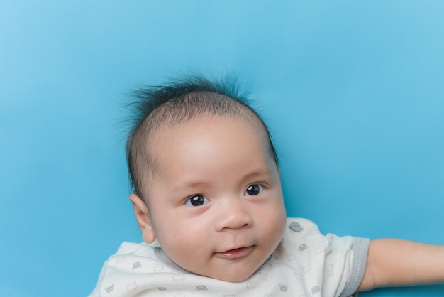 Portret van Aziatische babyjongen liggend op lichtblauw met een kopie ruimte