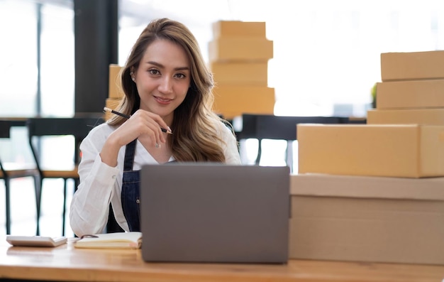 Portret van Aziatische jonge vrouw mkb werken met een doos thuis de werkplek opstarten kleine ondernemer kleine ondernemer mkb of freelance bedrijf online en levering concept