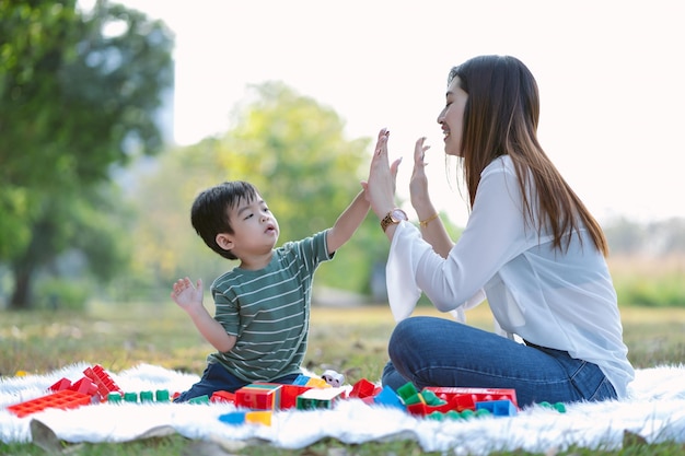 Portret van Aziatische moeder en zoontje in casual stijl geven high five en spelen samen