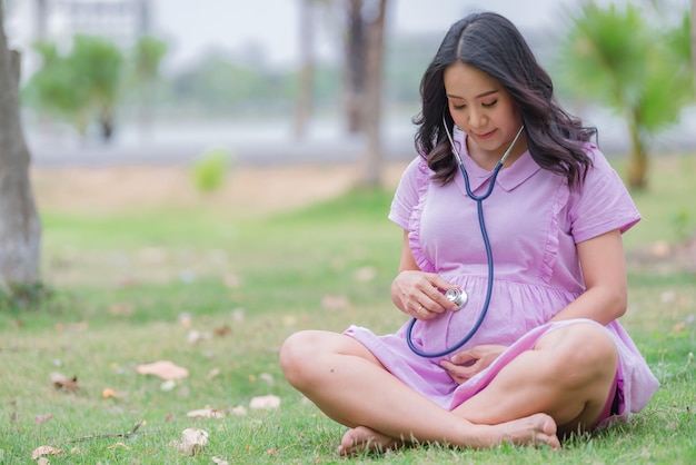 Portret van Aziatische mooie zwangere vrouw in het parkThailand-mensen Gelukkig vrouwenconcept Haar gebruikshand raakt haar buik aanMoederdagconcept