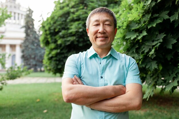 Portret van aziatische oudere man met shirt in park Koreaanse gepensioneerde staande met gekruiste armen