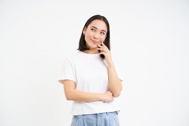 Portret van Aziatische vrouw denken opzoeken met nadenkend gezicht staande in t-shirt over witte backg