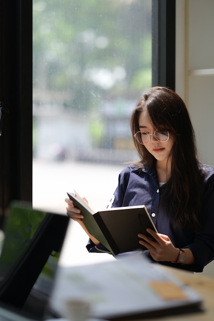 Portret van aziatische vrouw die een boek in bibliotheek leest