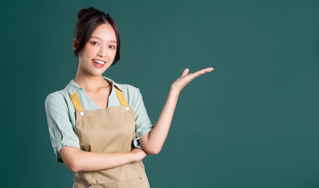 Portret van Aziatische vrouw die schort op groene achtergrond draagt