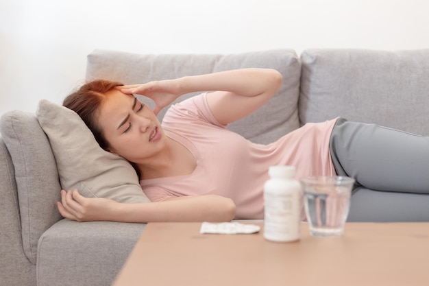 Portret van Aziatische vrouw houdt hun hand tegen hoofdpijn liggend op de bank, Jonge mooie Aziatische vrouw op de bank met hoofdpijn / migraine / stress / ziek