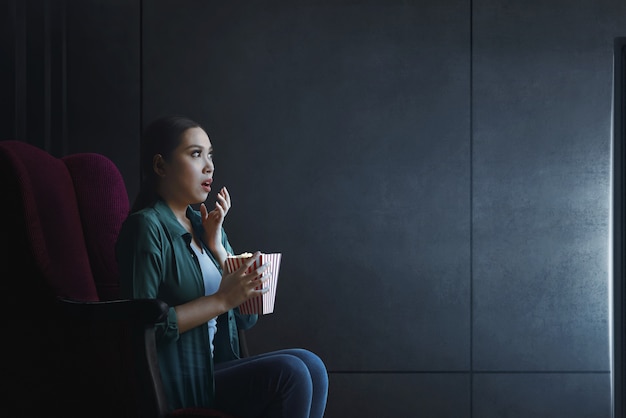 Portret van Aziatische vrouw met popcorn kijken naar horrorfilm