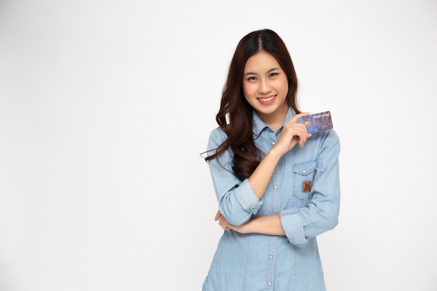 Portret van Aziatische vrouwen die de blauwe creditcard en de glimlach van het het overhemdsholding van Jean dragen die over witte muur, Jonge vrouw die, Gelukkig gevoelconcept wordt geïsoleerd
