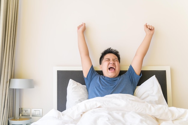 Portret van Aziatische zwaarlijvige jongen die wakker wordt op het bed