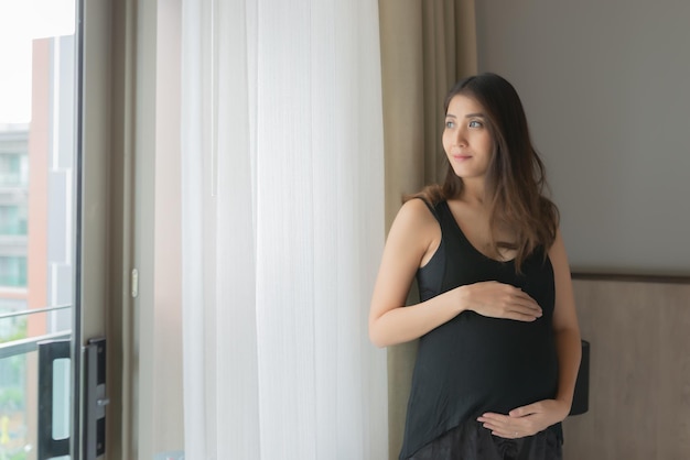 Portret van Aziatische zwangere vrouw in de slaapkamer