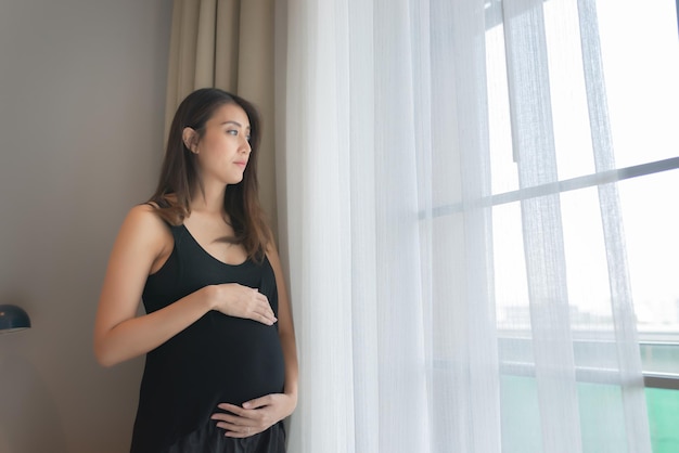 Portret van Aziatische zwangere vrouw in de slaapkamer