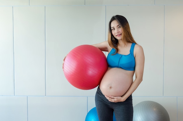 Portret van Aziatische zwangere vrouw oefenen in de sportzaal, met de grote bal