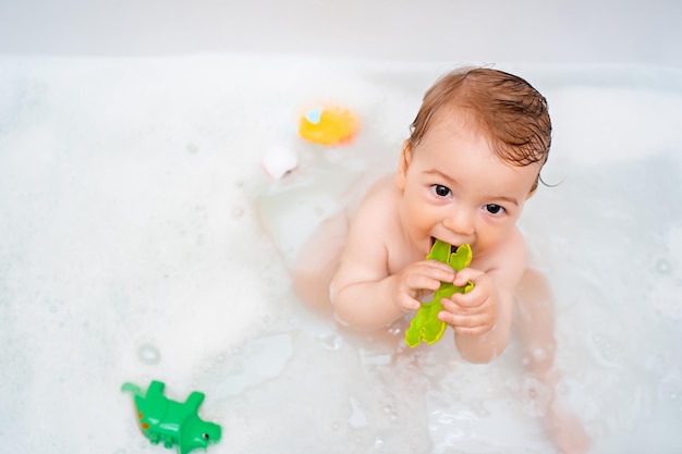 Portret van baby badend in wit bad vol schuim thuis dagelijks leven hygiëne kinderen levensstijl concept