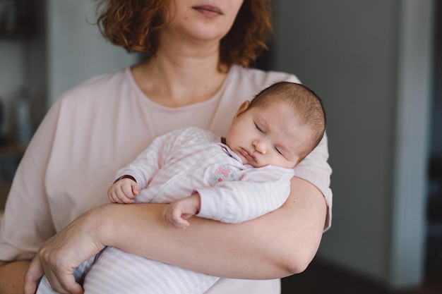 Portret van baby lief slapen op moeders handen Liefhebbende moeder die haar pasgeboren baby thuis draagt Moeder knuffelt haar kleine meisje van 1 maand oud