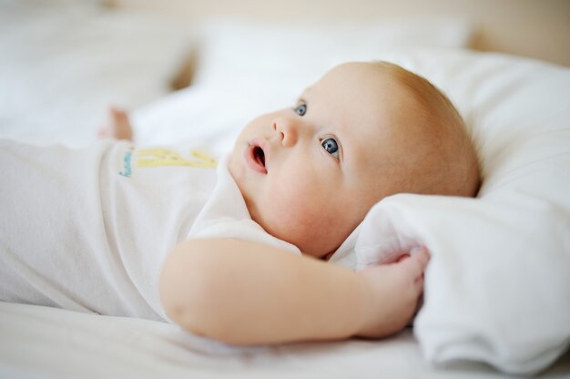 Portret van baby met blauwe ogen. Een kind dat op een bed rust