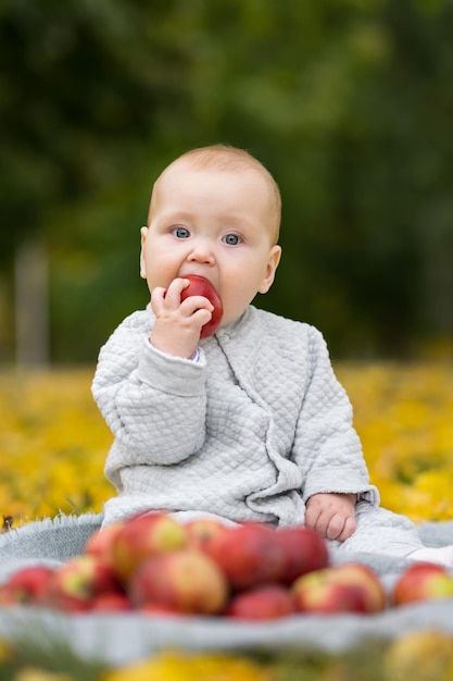 Portret van babymeisje in rompertjes die appel op plaid bijten