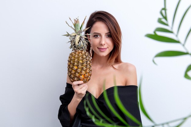 Portret van beautifyl vrouw met ananas en palmtak op witte achtergrond