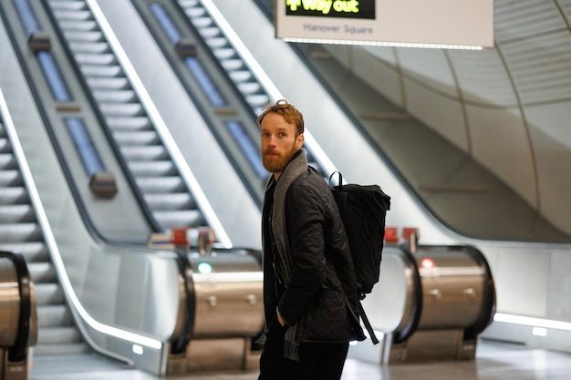 Portret van bebaarde man toerist met rugzak op achtergrond van roltrappen