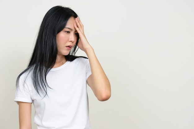 Portret van beklemtoonde jonge Aziatische vrouw die en hoofdpijn heeft