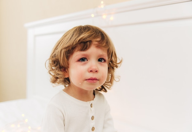 Portret van betraand meisje. Klein schattig meisje is cry.indoor.curly haar en blauwe ogen.