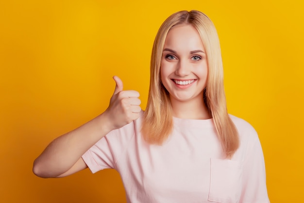 Portret van betrouwbare promotor lady toothy smile duim omhoog op gele achtergrond