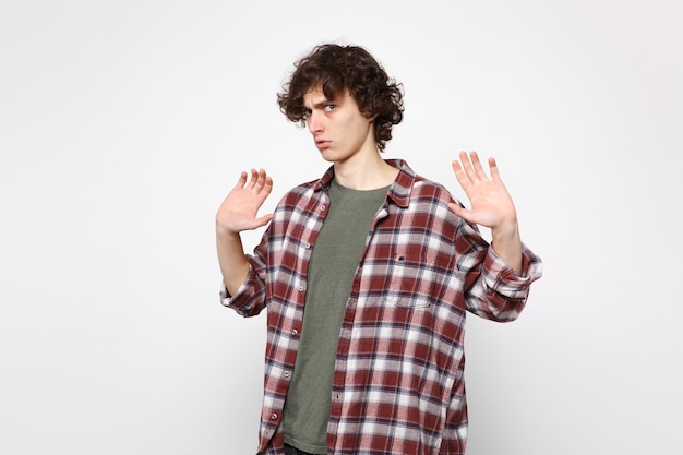 Portret van bezorgde verbijsterde jonge man in casual kleding stijgende handen, met palmen geïsoleerd op een witte muur achtergrond in de studio. Mensen oprechte emoties, lifestyle concept. Bespotten kopie ruimte.