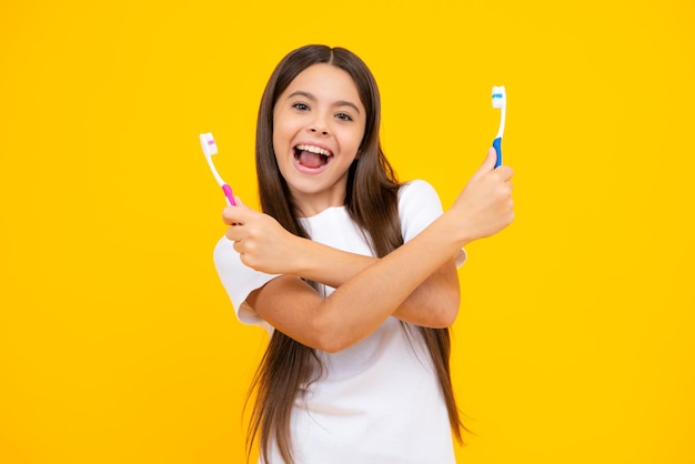 Portret van blanke tiener meisje houdt een tandenborstel haar tanden poetsen ochtend routine mondhygiëne geïsoleerd op gele achtergrond Opgewonden tiener blij verbaasd en dolblij emoties