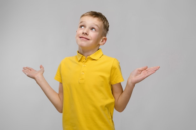 Portret van blonde blanke kleine jongen in geel t-shirt met open armen