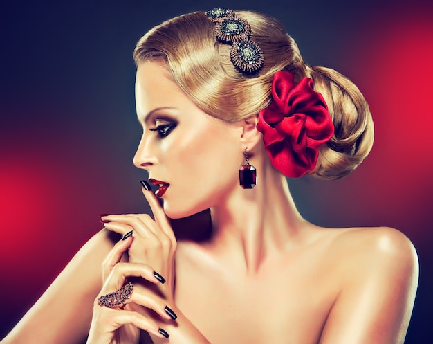 Portret van blonde donkerharige vrouw met elegante retro kapsel met grote knot van haar en heldere rode strik. Elegante kapsel, zwarte manicure, rokerige ogen stijl make-up op haar gezicht. Portret in profiel.