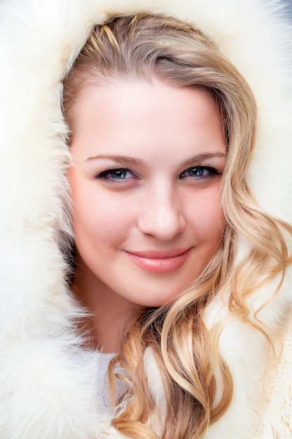 Foto portret van blonde jonge vrouw in bontjas bij de winterachtergrond