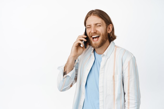 Portret van blonde man praten op mobiele telefoon en lachen, witte achtergrond.