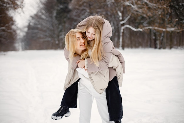 Portret van blonde moeder en tienerdochter die in het winterbos staan