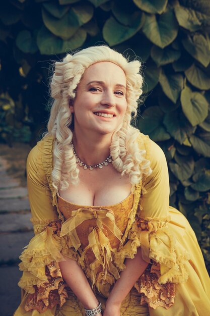 Foto portret van blonde vrouw gekleed in historische barokke kleding met ouderwets kapsel, buitenshuis. luxe middeleeuwse jurk