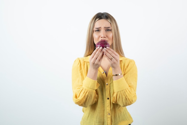 Portret van blonde vrouw met rode ui met droevige uitdrukking