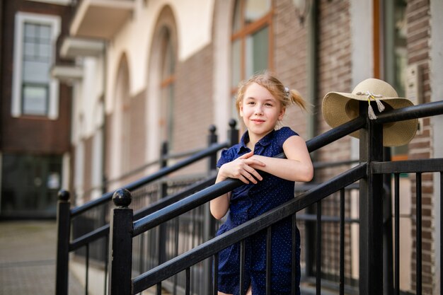 Portret van blondemeisje 10 jaar oud die onder mooie oude huizen spelen